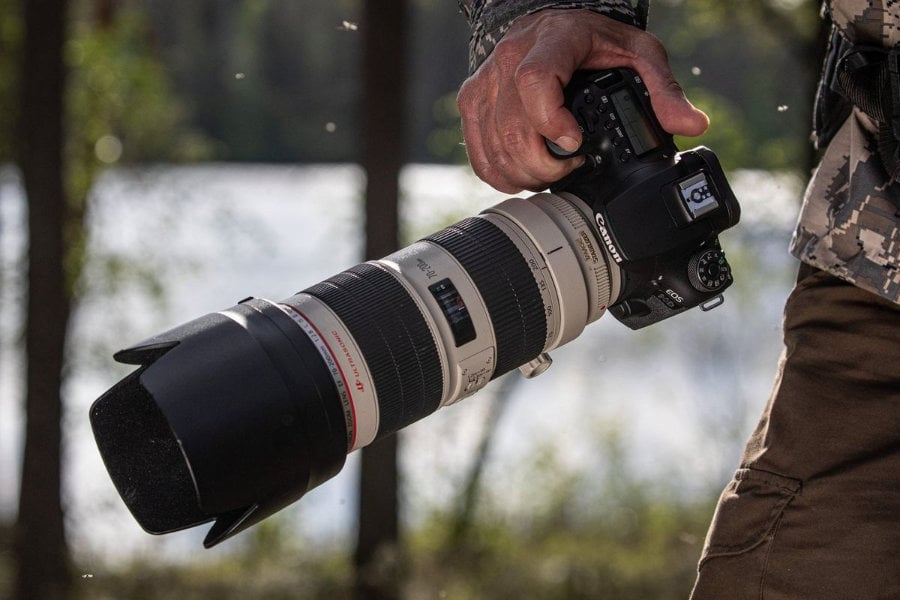  Photo of photographer holding Canon EOS 90D with telephoto lens attached<